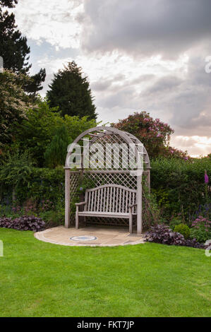 Wooden trellis seat arbour, mosaic art, lawn & summer border plants in beautiful, traditional, designed, landscaped garden - West Yorkshire, England.