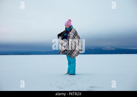 Caucasian teenage girl wrapped in blanket in snow