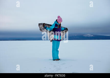 Caucasian teenage girl wrapped in blanket in snow