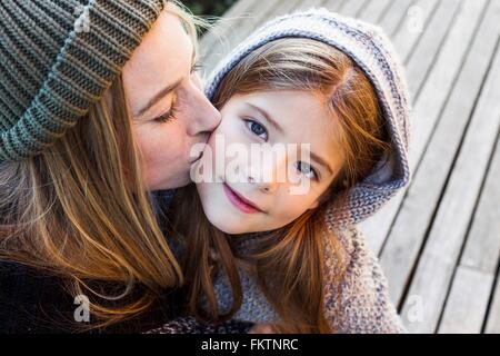 Mother kissing daughter on cheek, high angle portrait Stock Photo