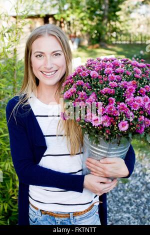 Mid adult woman holding bucket with flowers Stock Photo