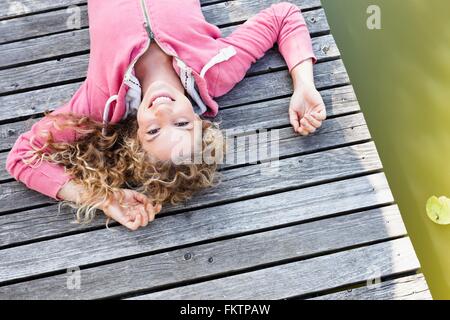 Young woman lying on wooden decking smiling to camera Stock Photo