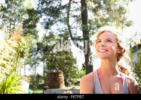 Young woman looking up smiling in sunlight, portrait Stock Photo