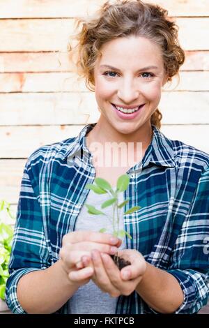 Young woman holding seedling, portrait Stock Photo