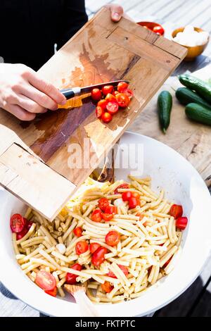 Woman scraping tomatoes into bowl with knife Stock Photo