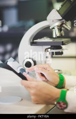 Scientist using digital tablet and optical microscope Stock Photo