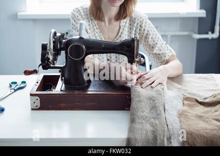 Cropped view of woman sewing textiles on vintage sewing machine Stock Photo