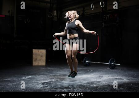 A young woman wearing a sports crop top and tight shorts skipping with a  skipping rope outside Stock Photo - Alamy