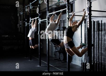 Male and female young adults training on wall bar in gym Stock Photo
