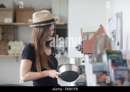 Young female waitress preparing food behind counter in cafe Stock Photo