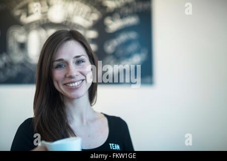 Portrait of young female waitress holding coffee in cafe Stock Photo