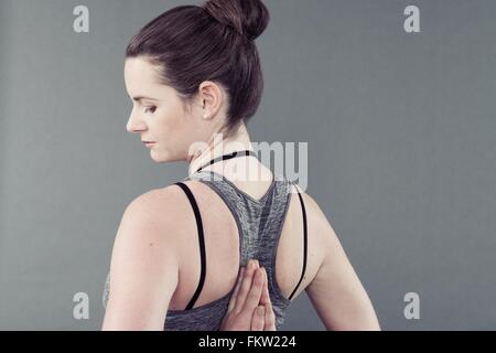Young woman practising yoga, grey background Stock Photo