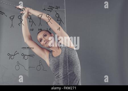 Young woman practising yoga in front of glass wall, grey background Stock Photo
