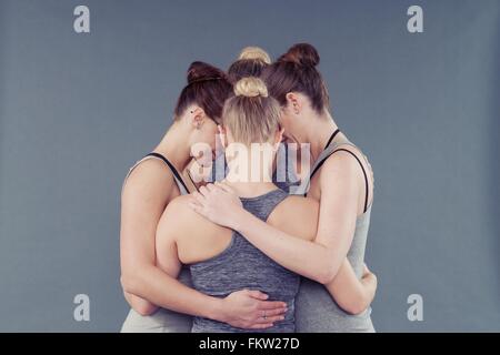 Young women in a huddle, grey background Stock Photo