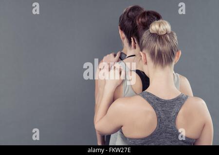 Young women in a line, holding shoulders, grey background Stock Photo