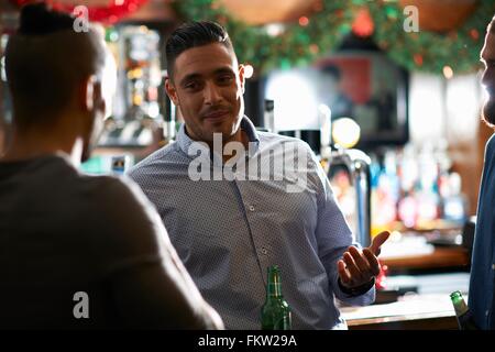 Man leaning against counter in public house talking to friend Stock Photo