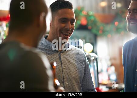 Young man in public house with friends smiling Stock Photo