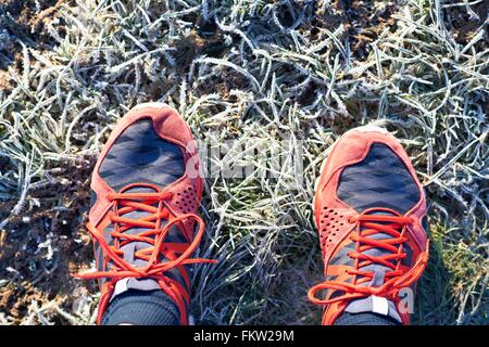 Overhead view of runners feet wearing running shoes on frosty grass Stock Photo