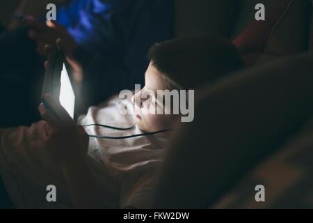 High angle view of boy on sofa wearing earphones using digital tablet Stock Photo