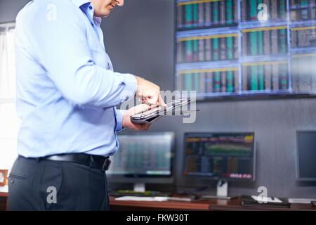 Side view of young mid adult mans mid section in office using digital tablet Stock Photo