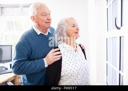 Senior couple in office looking out of window smiling Stock Photo