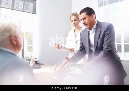 Business man and business woman in office having discussion with senior customer Stock Photo