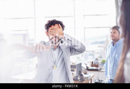 Mature man in team building task, holding hands covering eyes Stock Photo
