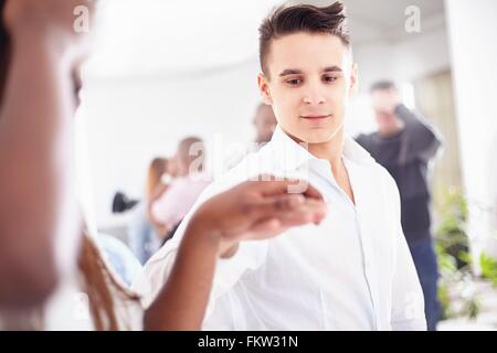 Young man in team building task holding colleagues hand Stock Photo