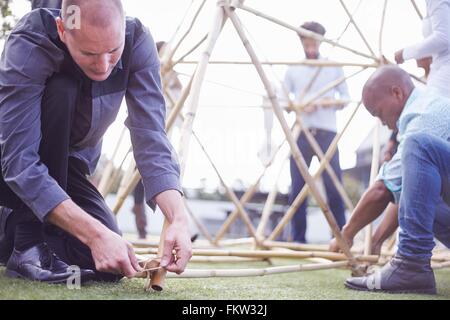 Colleagues kneeling down building wooden structure Stock Photo