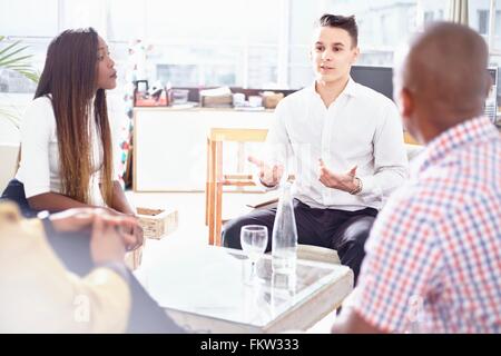 Colleagues sitting around c fee table chatting Stock Photo