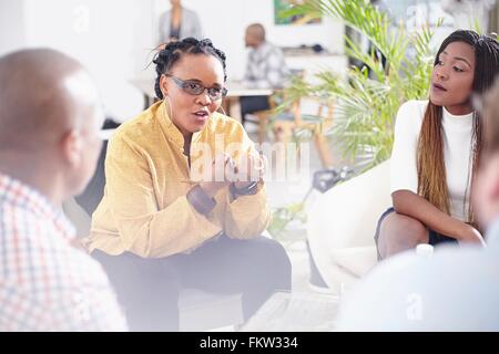 Mature woman talking to colleagues, hand gestures Stock Photo