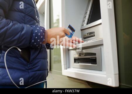 Young woman using cash machine, mid section Stock Photo