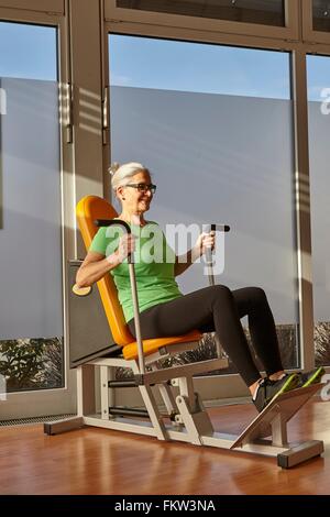 Mature woman doing sit down exercise on gym exercise machine Stock Photo