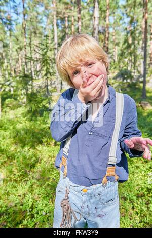 Portrait of young boy wearing retro clothes eating berries in forest Stock Photo