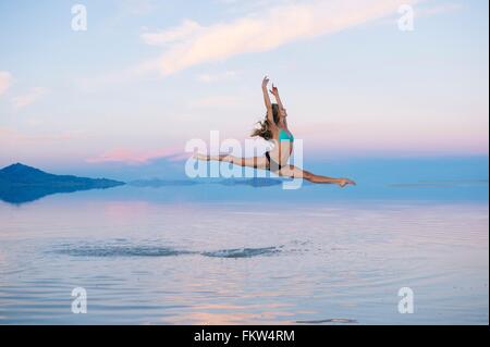 Female ballet dancer jumping mid air over lake, Bonneville Salt Flats, Utah, USA Stock Photo