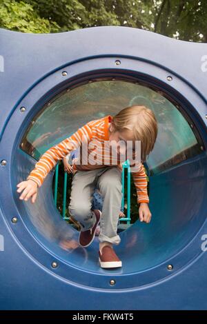 Boy bending forward in playground tunnel Stock Photo