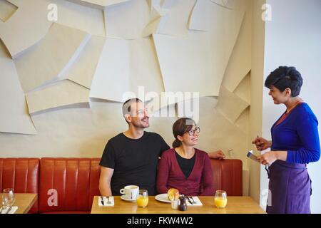 Waitress taking order in restaurant from mid adult couple Stock Photo