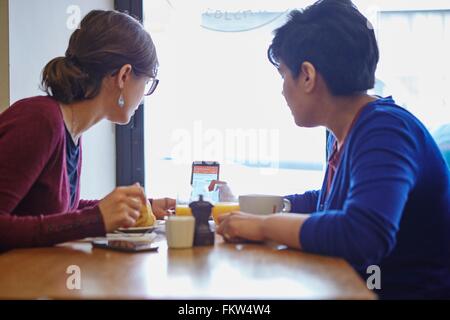 Two women reading smartphone text in restaurant Stock Photo