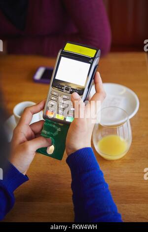 Close up of womans hands inserting card into credit card machine in restaurant Stock Photo