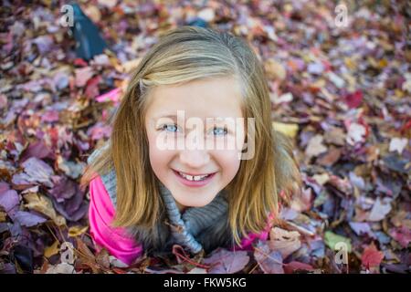 Girl lying on autumn leaves in garden Stock Photo
