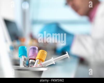 Blood samples for medical testing on desk, doctor in background Stock Photo