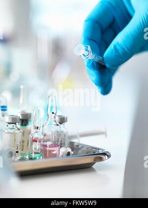 Doctor placing syringe back onto tray with drug vials Stock Photo