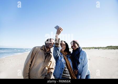 Three friends on beach, taking self portrait, using smartphone Stock Photo
