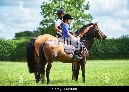 Side view of mature woman and girl horseback riding, looking away Stock Photo
