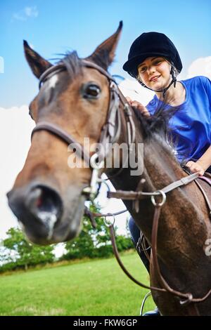 Low angle view of girl on horseback wearing riding hat smiling