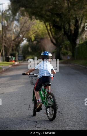 Boy riding bicycle in middle of road Stock Photo