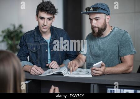 Two young men making query at office reception Stock Photo