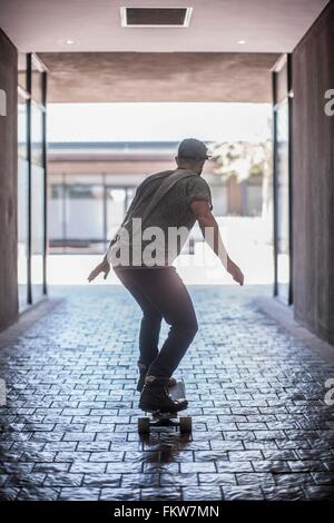 Rear view of young male skateboarder skateboarding in city Stock Photo