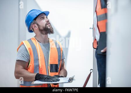 Construction worker talking to foreman from doorway of cabin on construction site Stock Photo