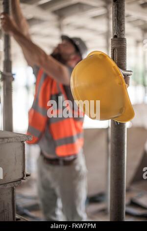 Male builder working on scaffolding on construction site Stock Photo